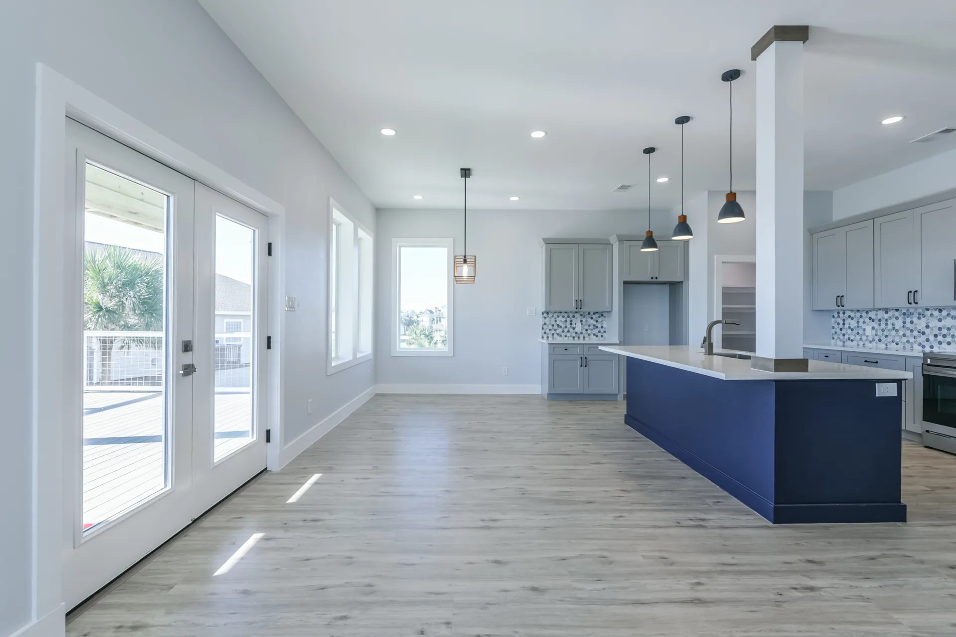 Open living and kitchen area at 11 Mile with white cabinetry, navy island, and light wood-look flooring