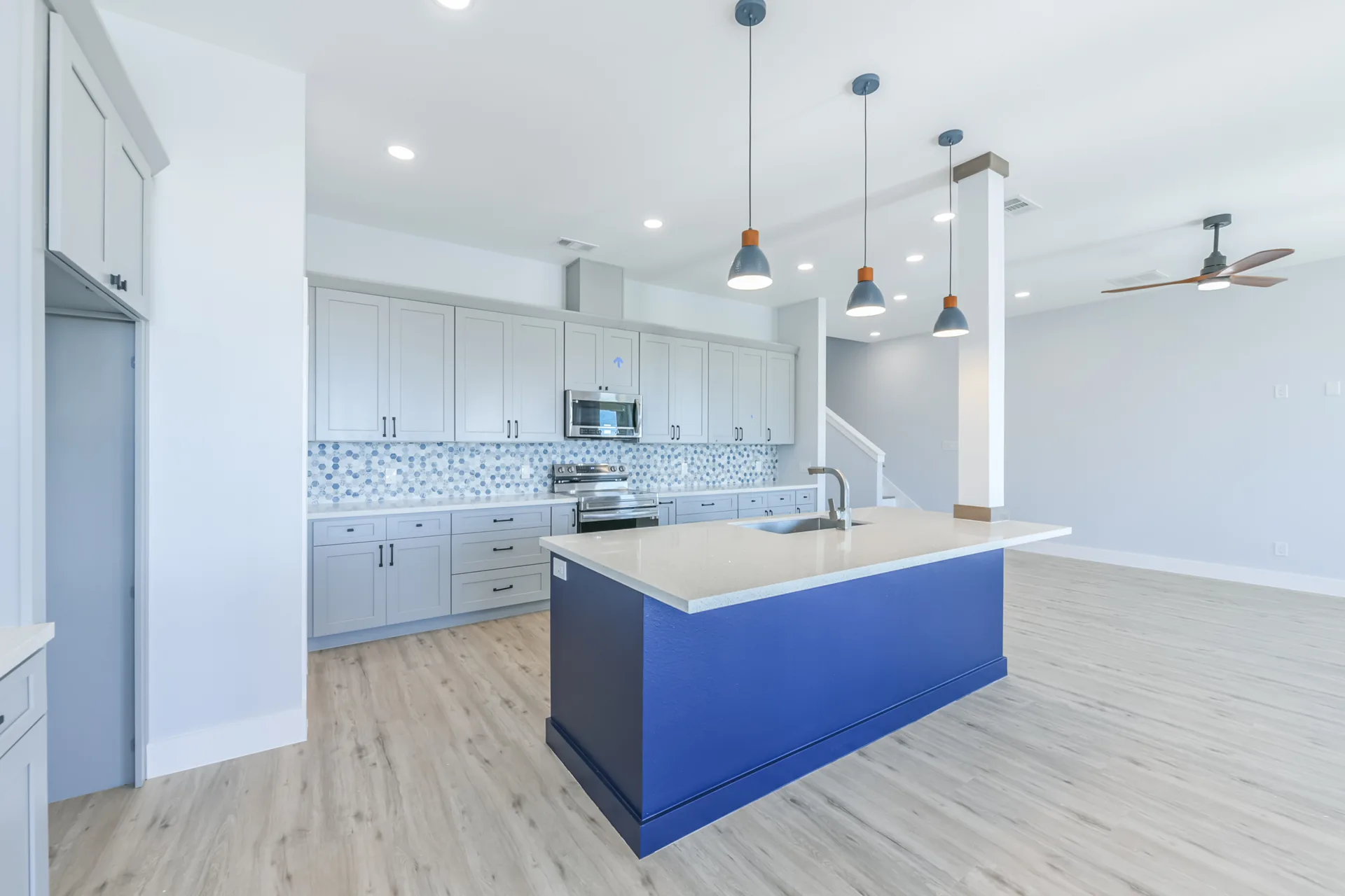 Kitchen at 11 Mile centered on a deep navy island with quartz counters and pendant lighting