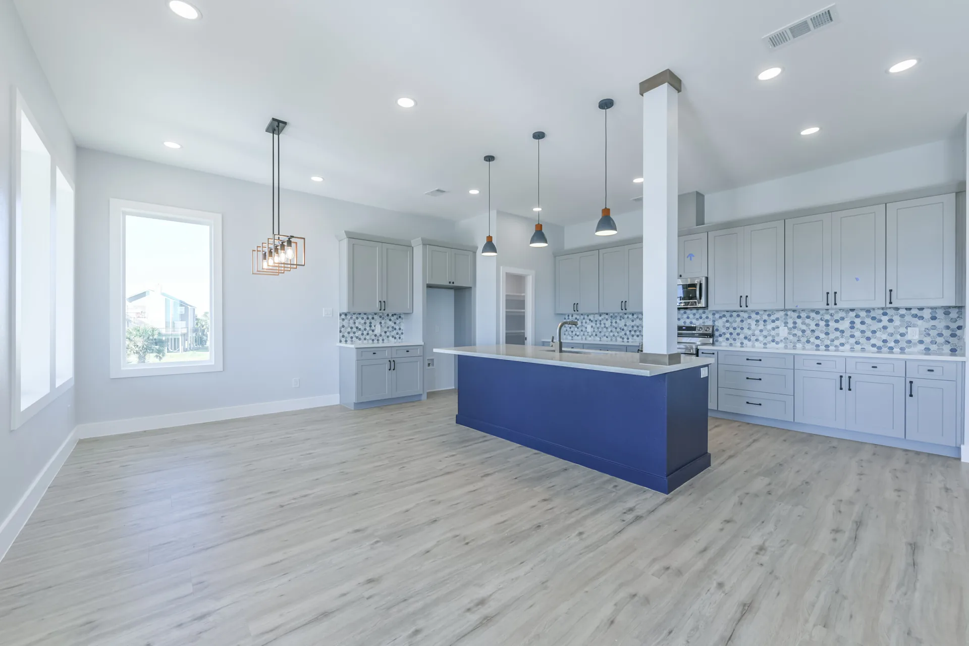Navy kitchen island at 11 Mile with pendant lights, bar seating, and blue hexagonal tile backsplash