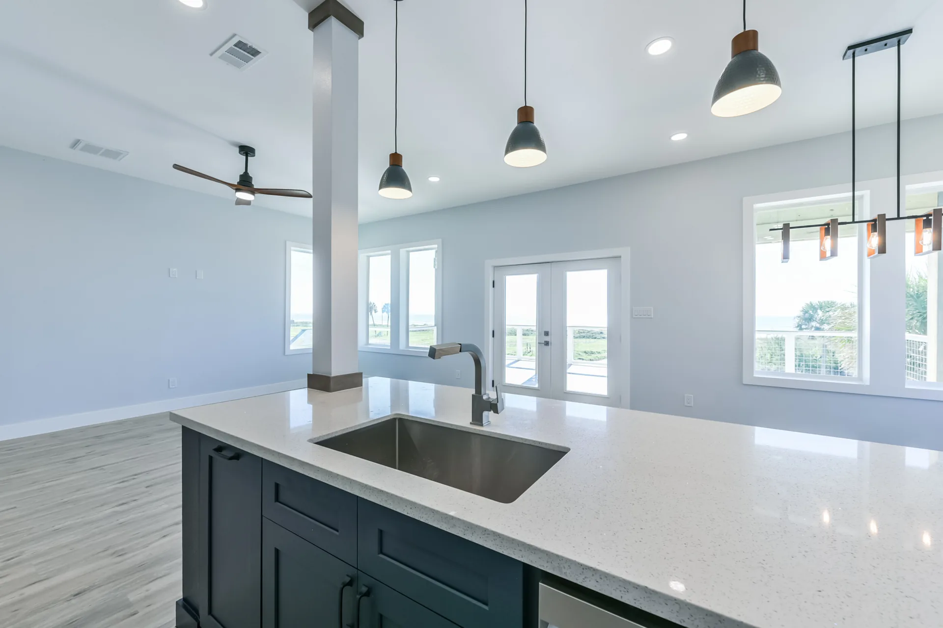 Close view of the 11 Mile island sink with quartz counter, matte black faucet, and pendant lighting