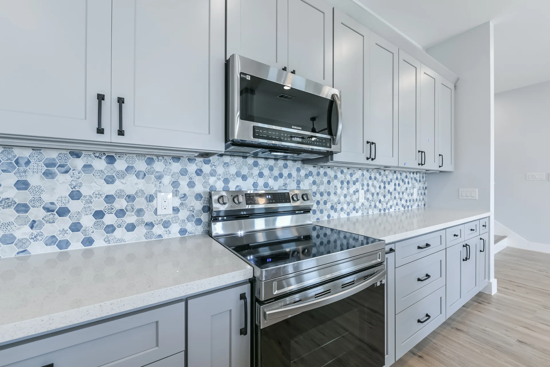 Range wall at 11 Mile with stainless slide-in range, microwave, and blue hexagonal mosaic backsplash
