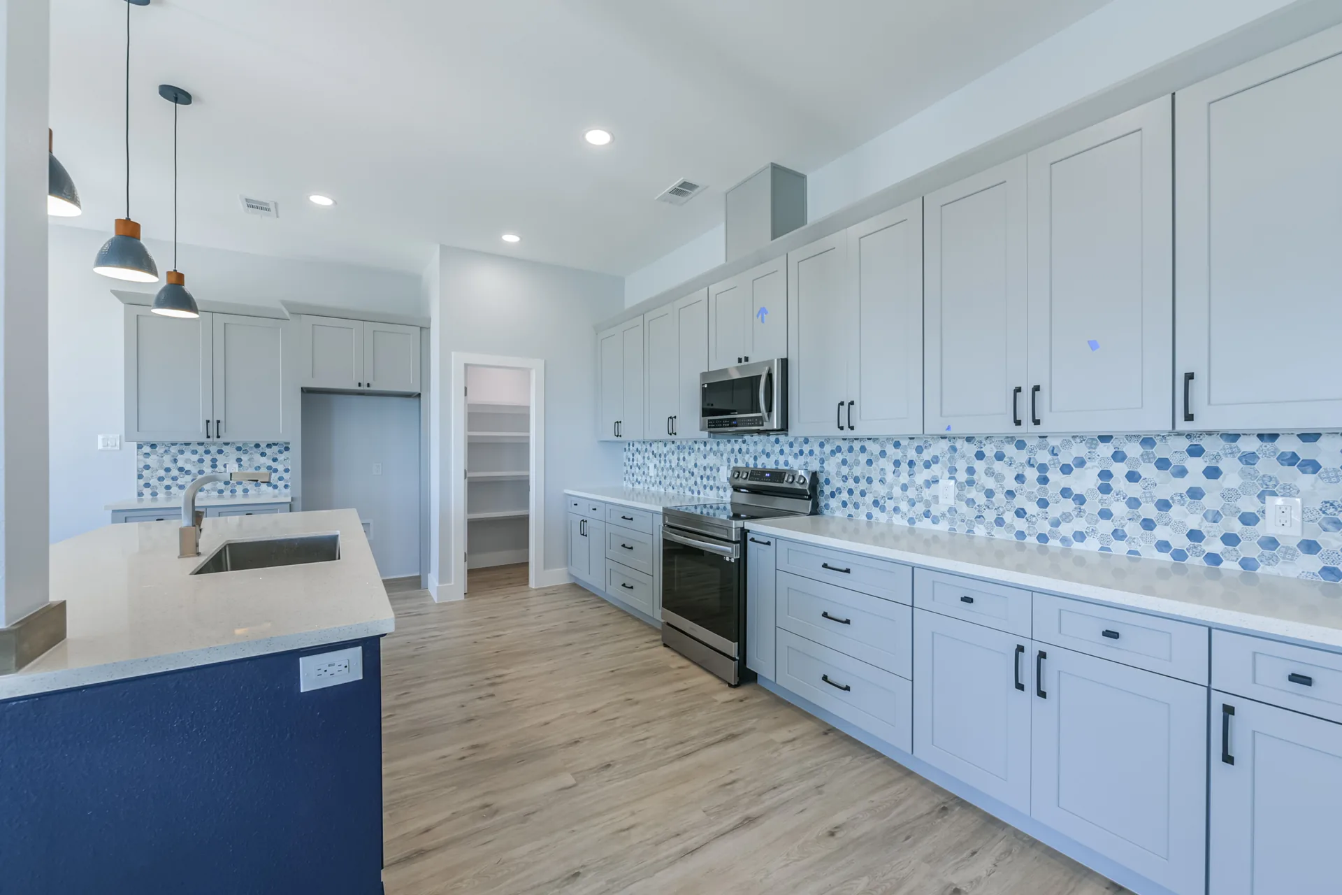 Full run of cabinetry and blue hex tile backsplash along the 11 Mile kitchen wall
