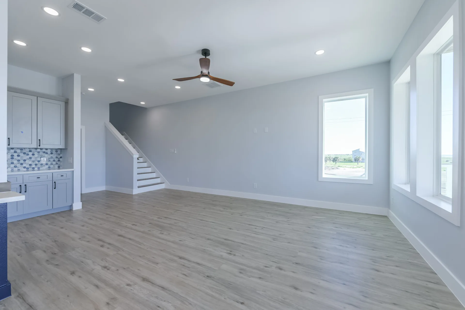 Living room at 11 Mile with vaulted ceiling, staircase, and windows on multiple walls