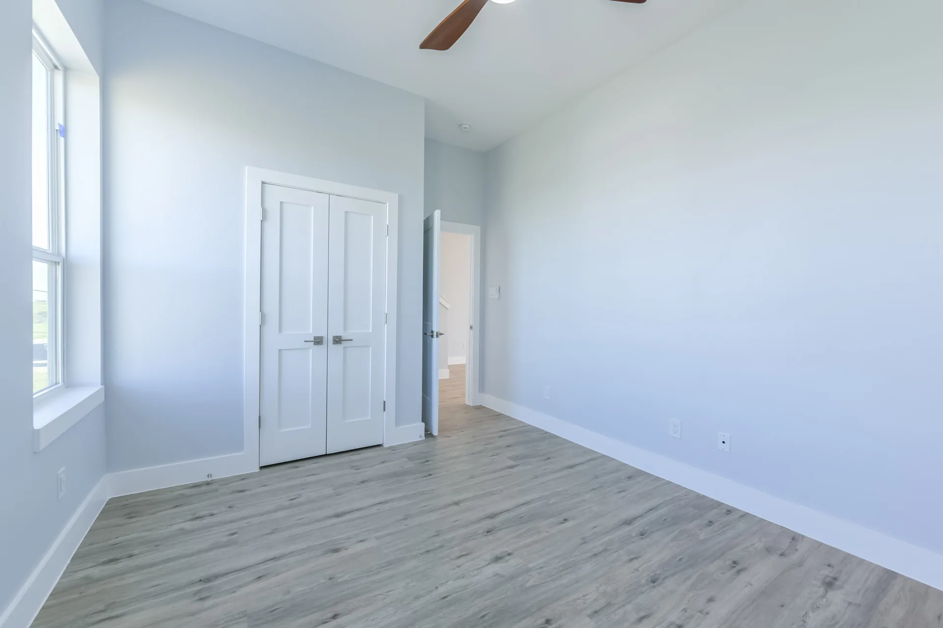 Guest bedroom at 11 Mile with soft blue walls, ceiling fan, and windows on two sides