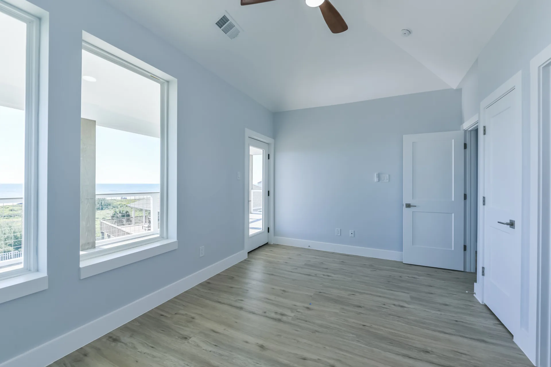 Bedroom at 11 Mile with a window framing the Gulf horizon and a modern ceiling fan