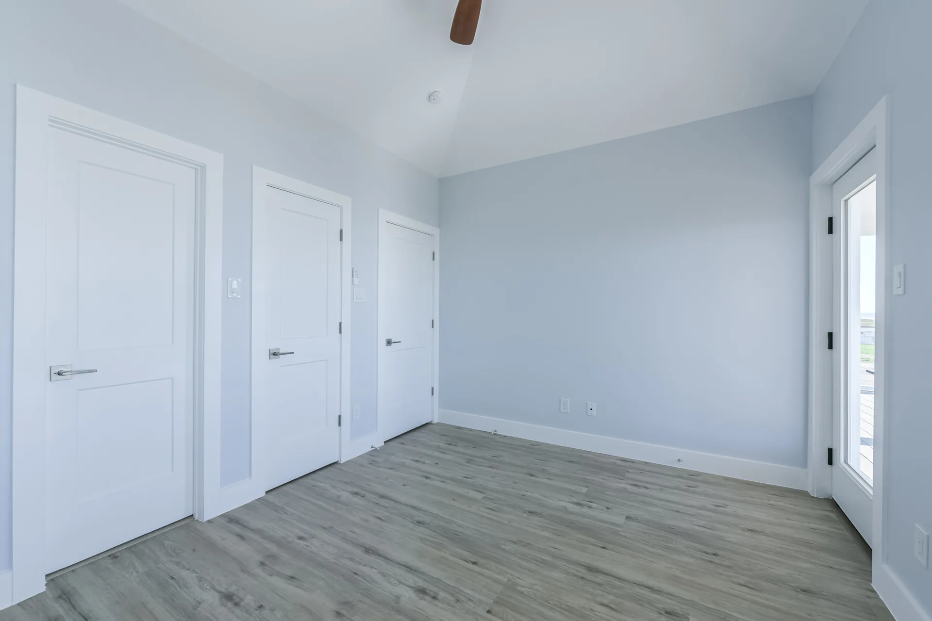 Bedroom at 11 Mile with wood-look flooring, vaulted ceiling, and coastal blue paint