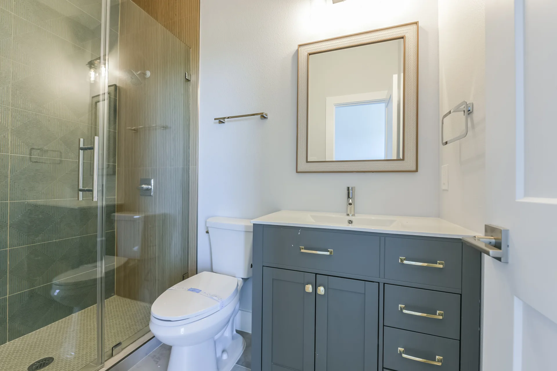 Full bath at 11 Mile pairing a glass shower with a grey vanity and framed mirror