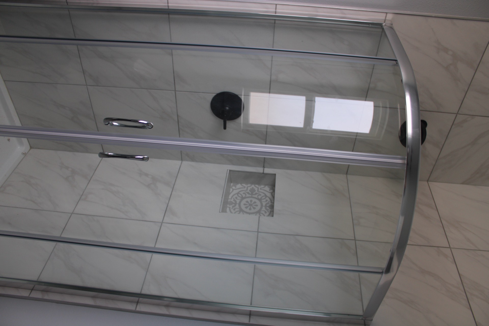 Living room viewed from the kitchen with clean contemporary lines, neutral furnishing tones, and natural light flooding through large coastal windows