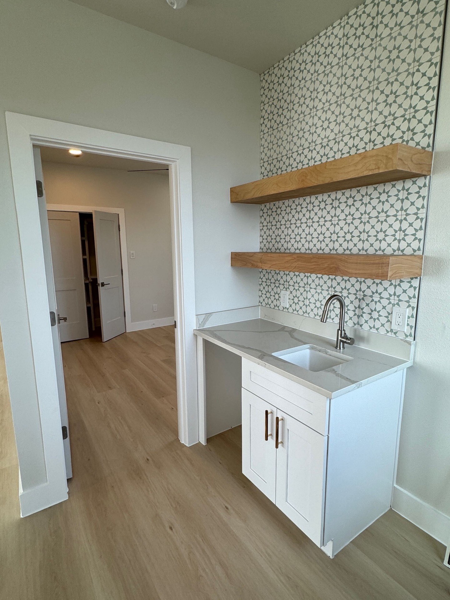 Kitchen sink area with window overlooking the Gulf, white shaker cabinets below, and brass faucet fixture