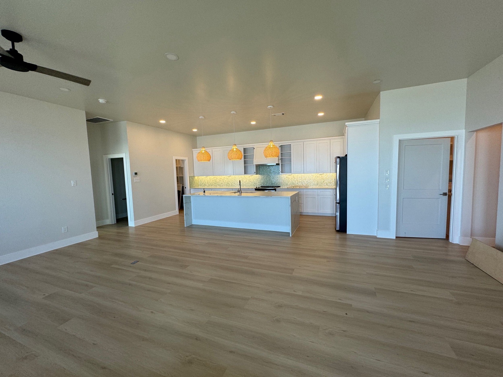 Primary bedroom from the entry showing neutral tones, recessed lighting, and panoramic balcony access through floor-to-ceiling glass