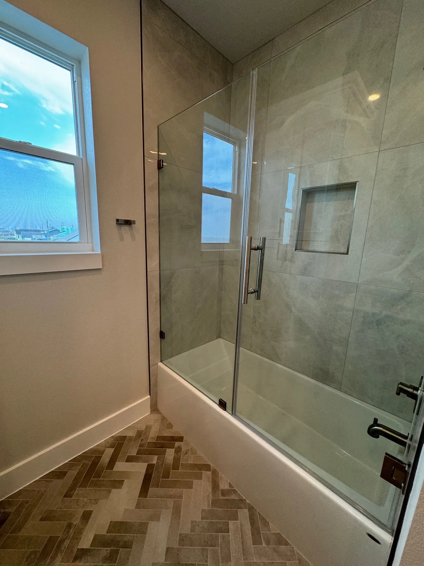 Primary bath dual vanity area with matching gray cabinets, marble surfaces, arched mirrors, and gold sconce lighting