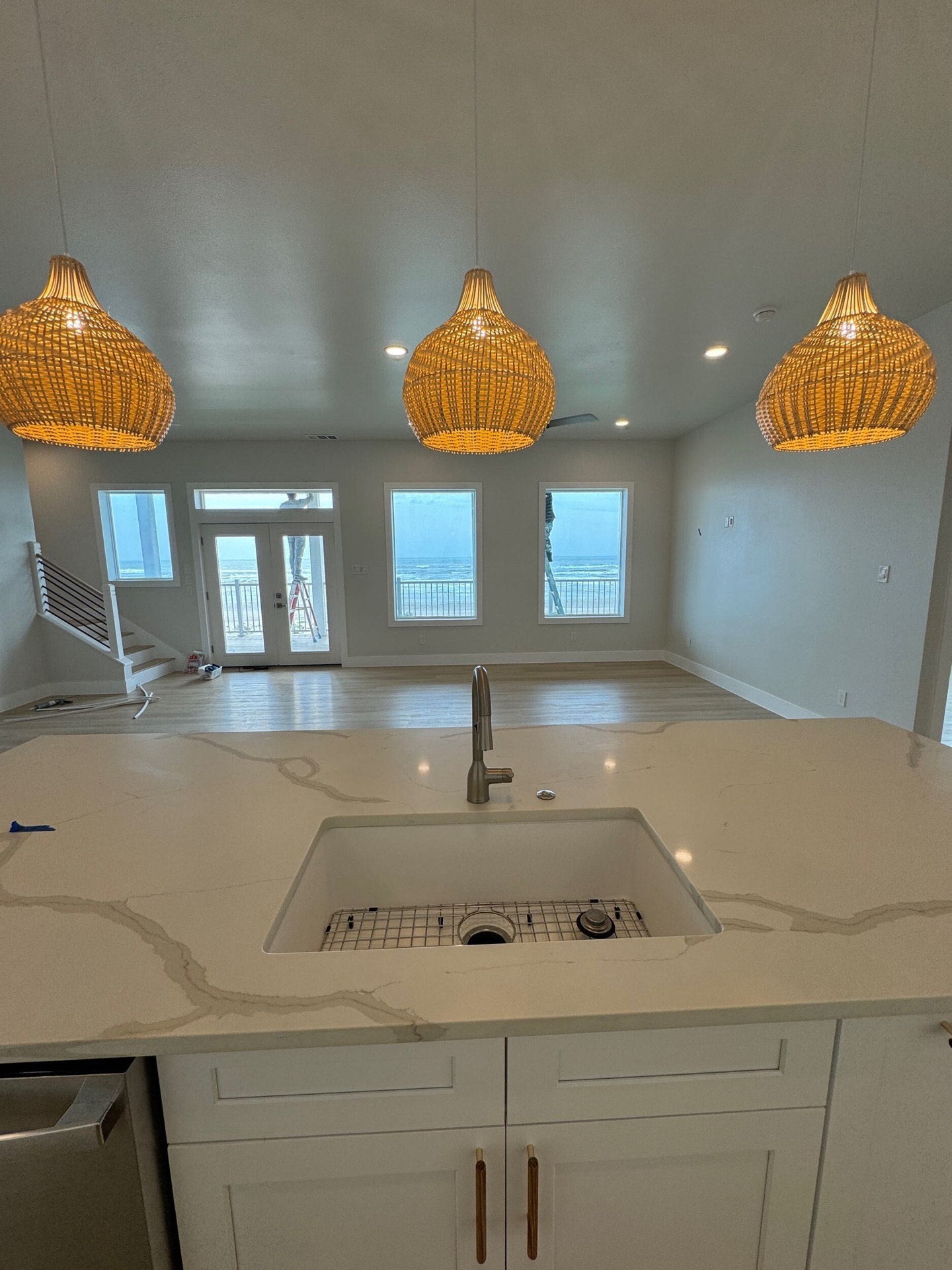 Fourth bathroom vanity detail showing marble countertop edge profile, brass cabinet pulls, and soft coastal color tones