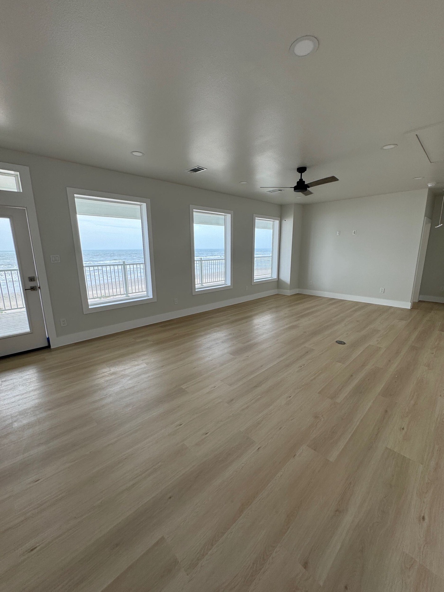 Upper-level wraparound porch with white railing, ceiling fans, and sweeping Gulf of Mexico views stretching to the horizon