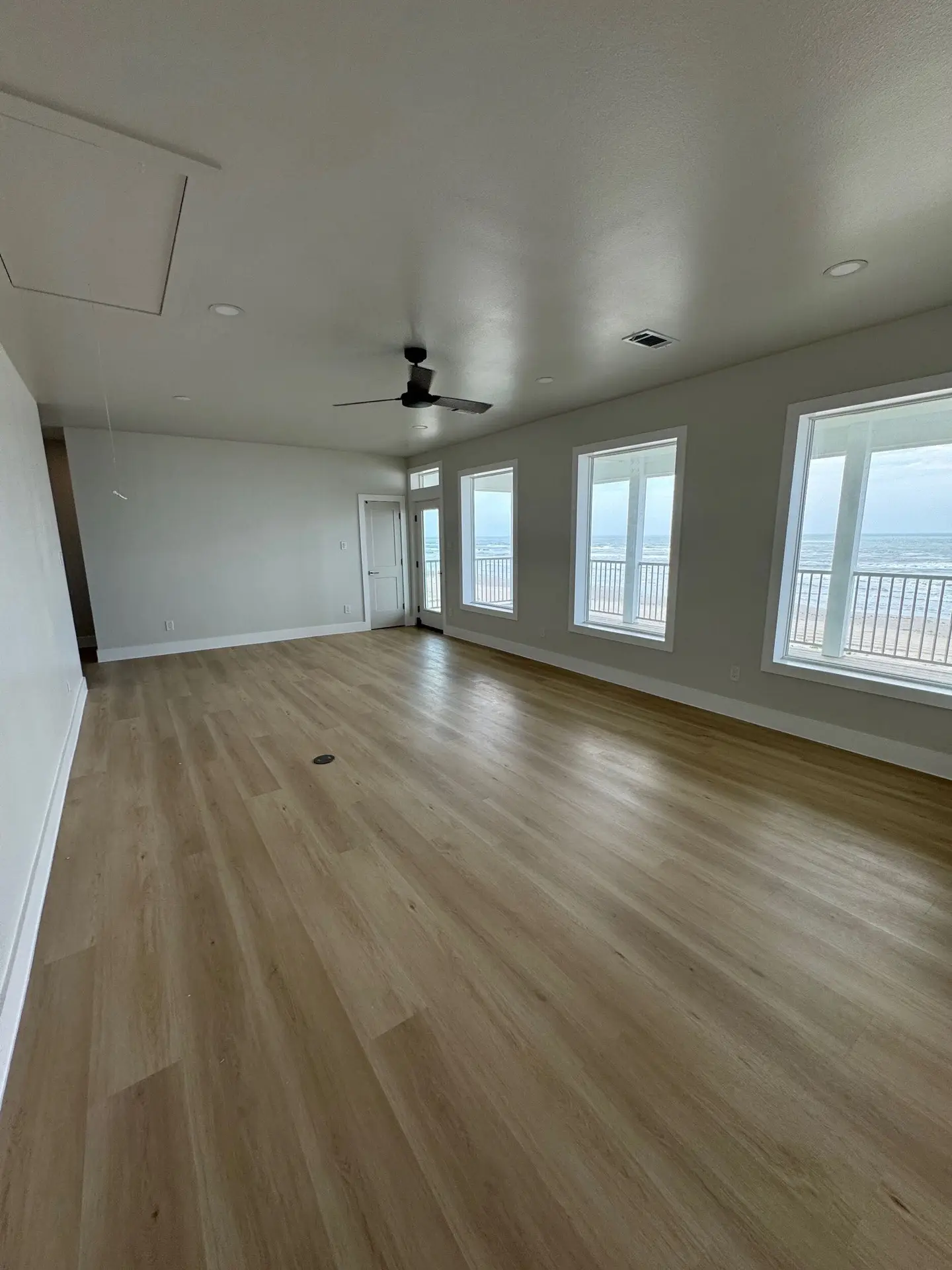 Lower covered porch running the full width of the home with durable composite decking and coastal white railing details