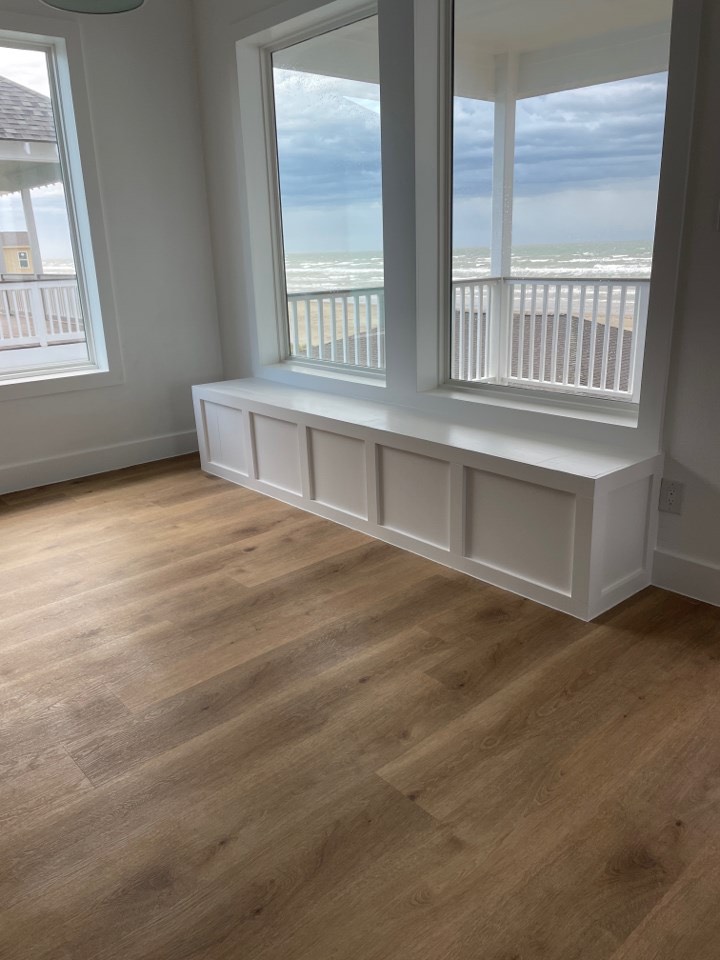 White upper cabinetry with glass-front doors and gold pulls complementing the navy lower cabinets in the Gulf Drive gourmet kitchen