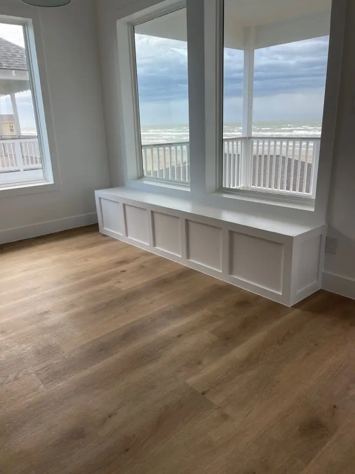 White upper cabinetry with glass-front doors and gold pulls complementing the navy lower cabinets in the Gulf Drive gourmet kitchen