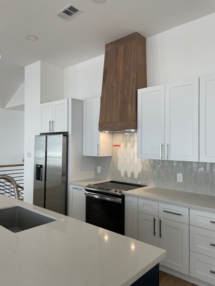 Living room adjacent to the kitchen with light oak floors, large windows, and coastal-inspired neutral furnishings at 131 Gulf Drive
