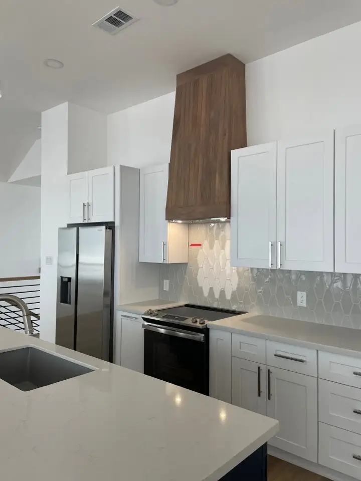 Living room adjacent to the kitchen with light oak floors, large windows, and coastal-inspired neutral furnishings at 131 Gulf Drive