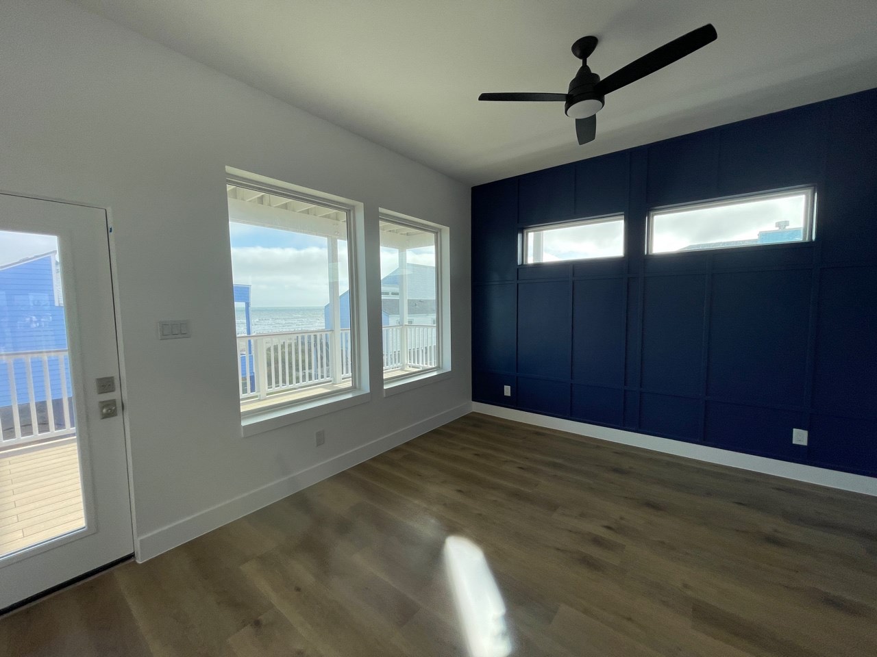 Soaring two-story great room with floor-to-ceiling marble fireplace surround, upper loft overlook, and dramatic vertical windows at 131 Gulf Drive