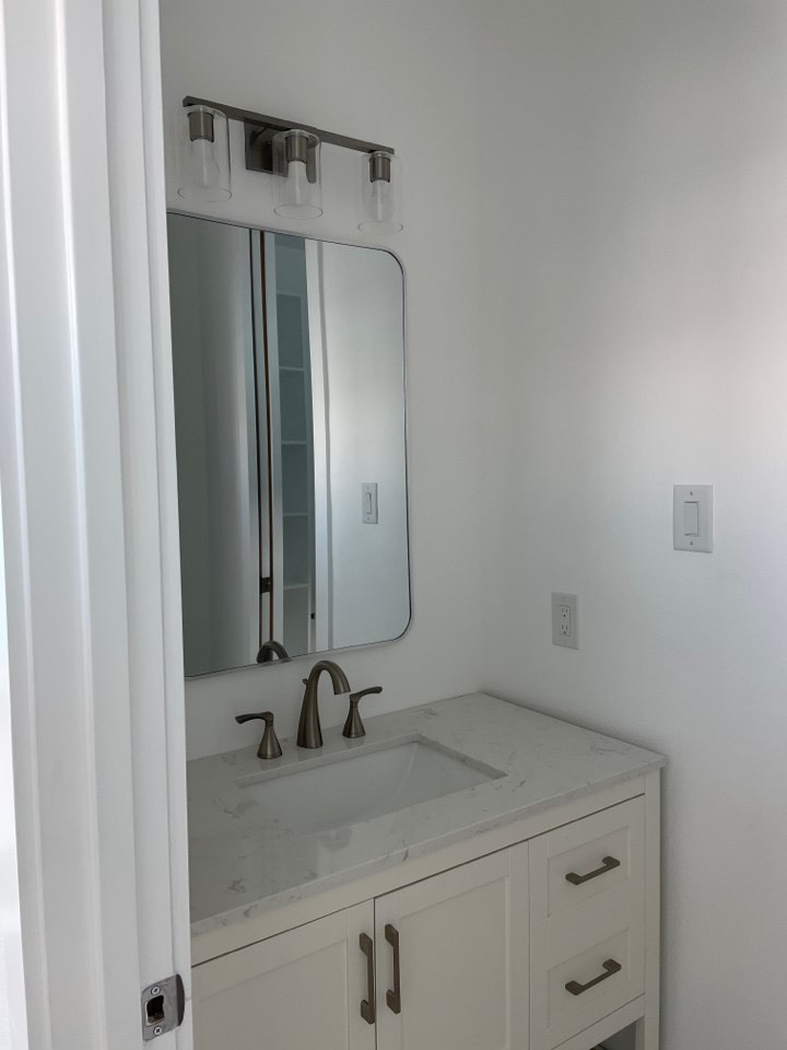 Spa-like master bathroom featuring a jetted soaking tub, floor-to-ceiling marble shower walls, and navy blue double vanity with gold fixtures