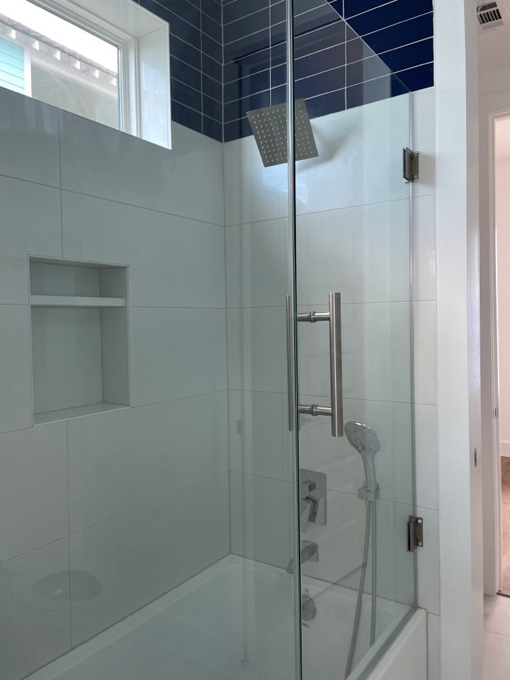 Walk-in marble shower with frameless glass enclosure, rain showerhead, and gold brass shower fixtures in the master bathroom