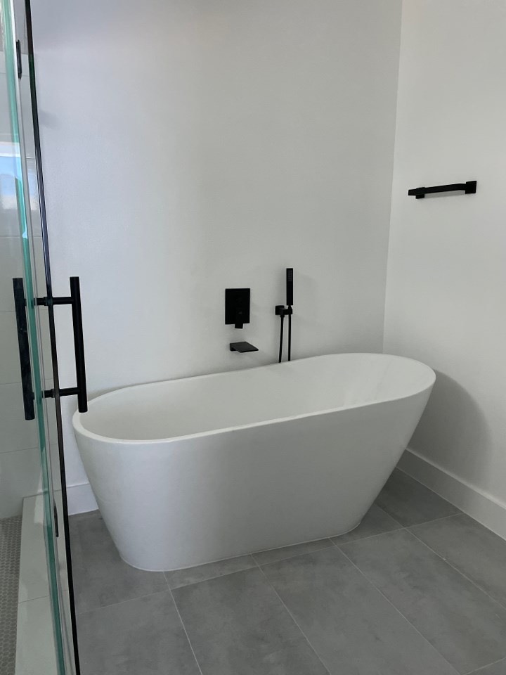 Gold and brass bathroom fixtures detail including towel bar, robe hook, and toilet paper holder against white marble tile walls
