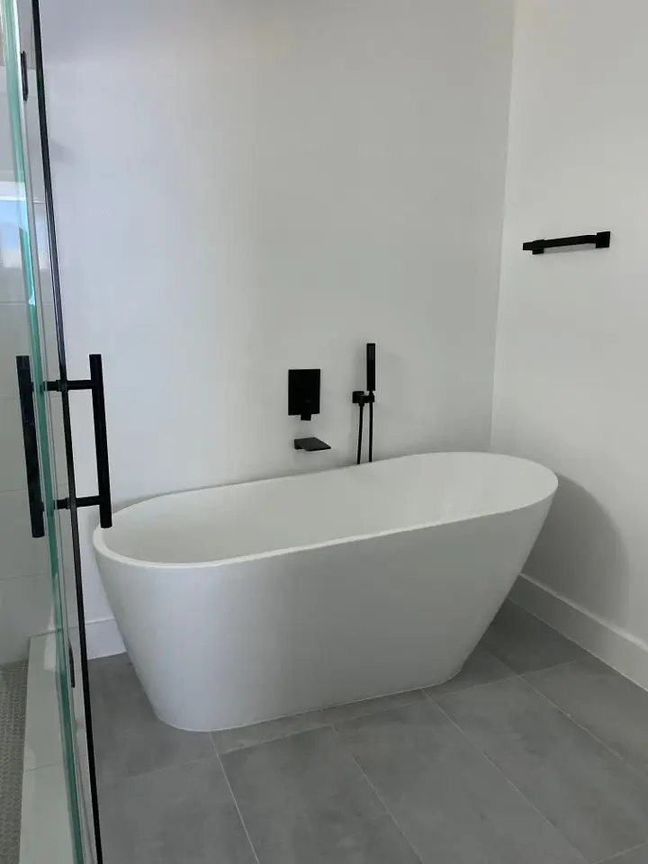 Gold and brass bathroom fixtures detail including towel bar, robe hook, and toilet paper holder against white marble tile walls