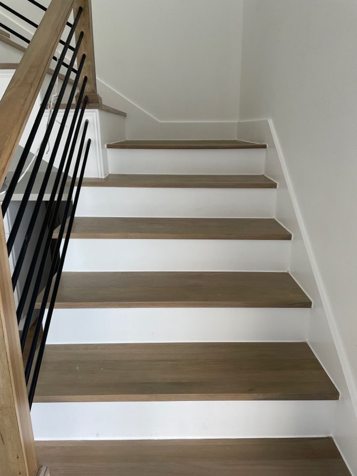 Fourth bedroom configured as a flex space with built-in desk area and light oak flooring in the modern coastal home