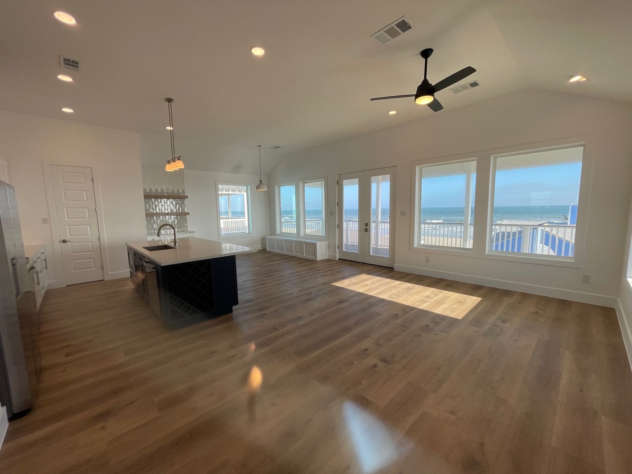 Modern open staircase with natural wood treads, sleek black metal railing and balusters connecting both levels of the coastal home