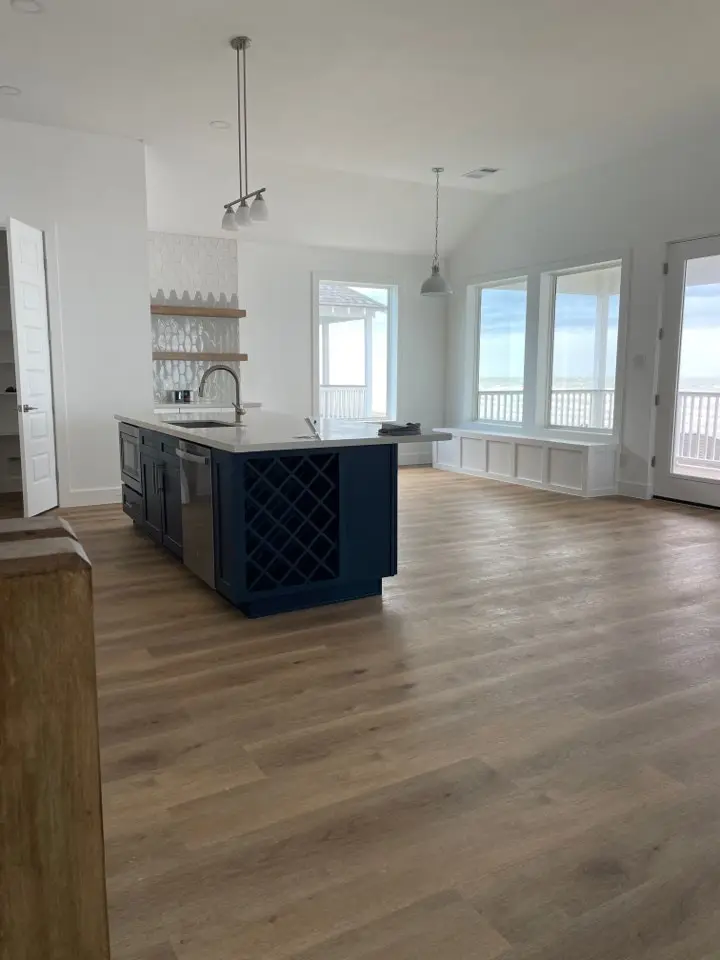 Custom wood range hood above professional stainless steel range with white quartz backsplash and navy blue surrounding cabinetry