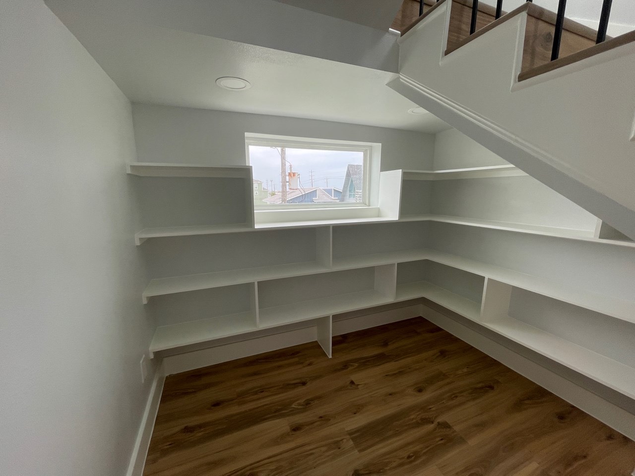 Kitchen and dining area bathed in natural light from floor-to-ceiling windows with clean coastal finishes and modern pendant lighting
