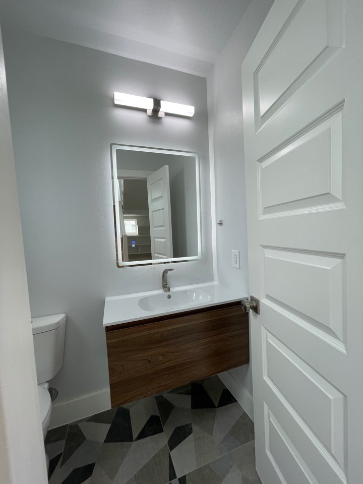 Bathroom with modern fixtures and clean coastal finishes complementing the light wood-look flooring found throughout 227 Gulf Drive