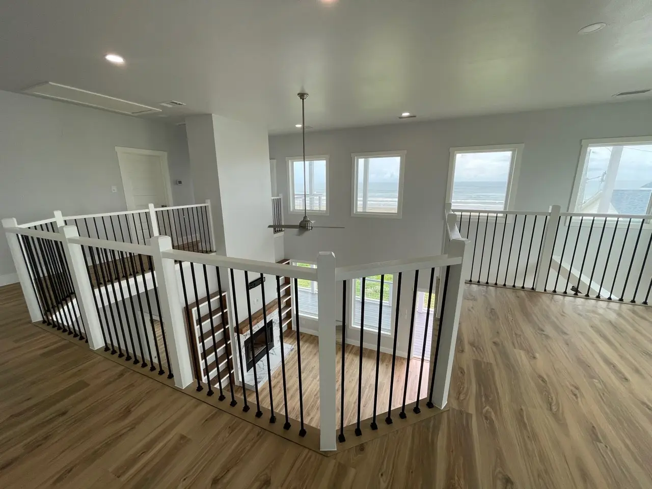 Side angle of the three-story coastal home revealing ground-level garage beneath the elevated structure with hurricane-rated piling foundation