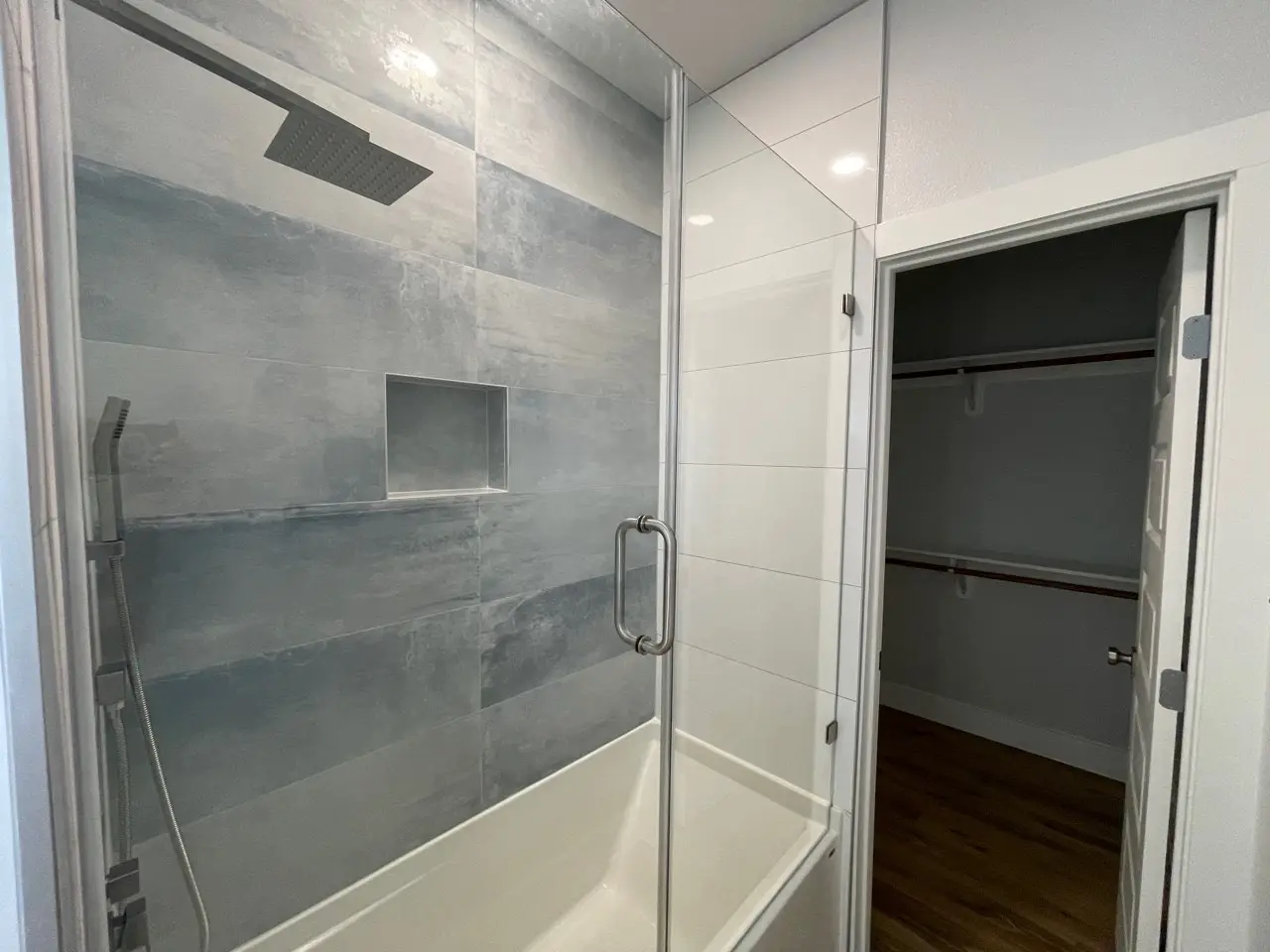 Rear exterior of 227 Gulf Drive featuring expansive windows on all three levels, steel blue siding, and white metal railing balconies facing the coast