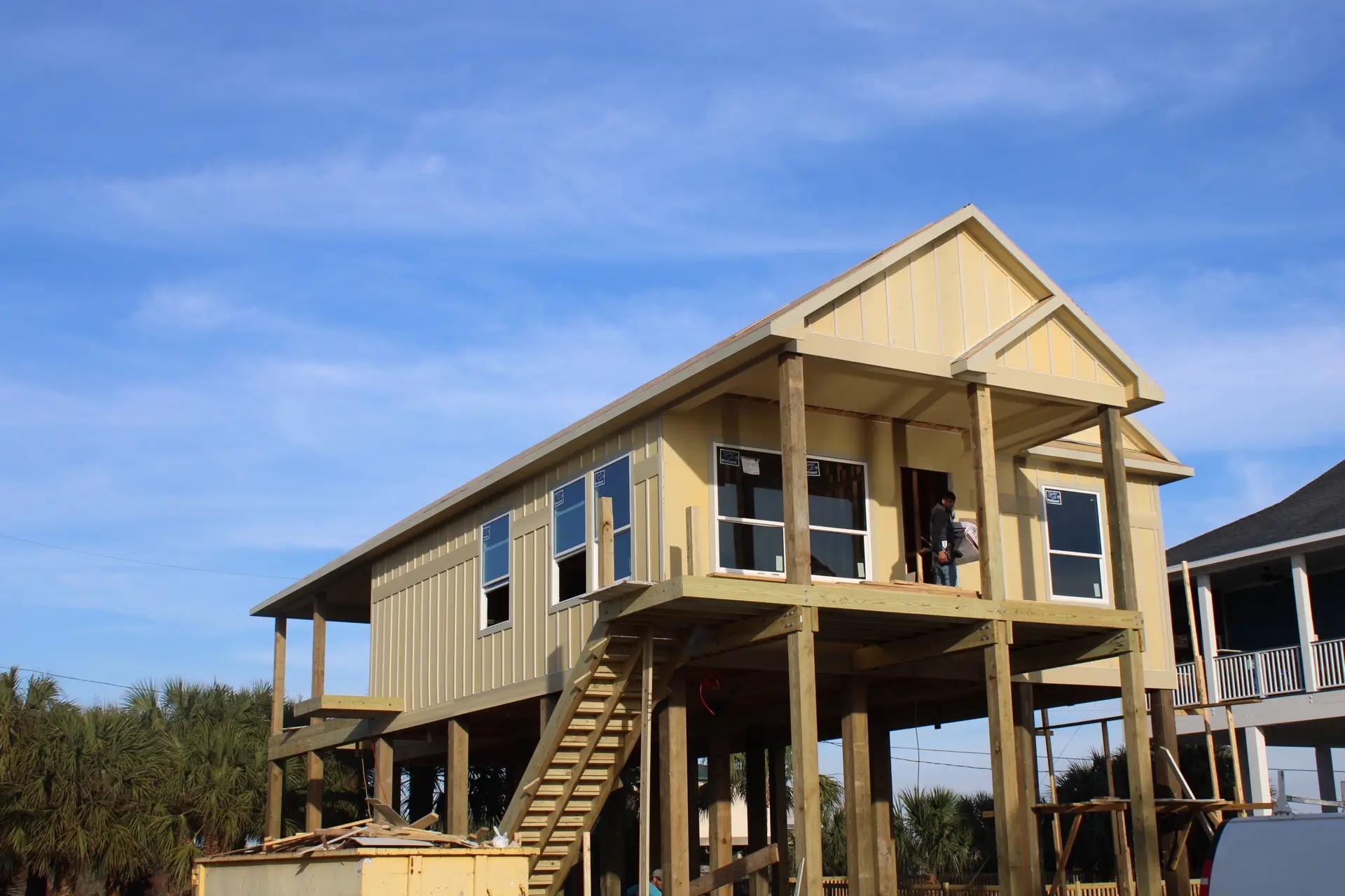 Secondary bedroom with warm brown accent wall, modern ceiling fan, and neutral coastal color palette in the Tiki Island cottage