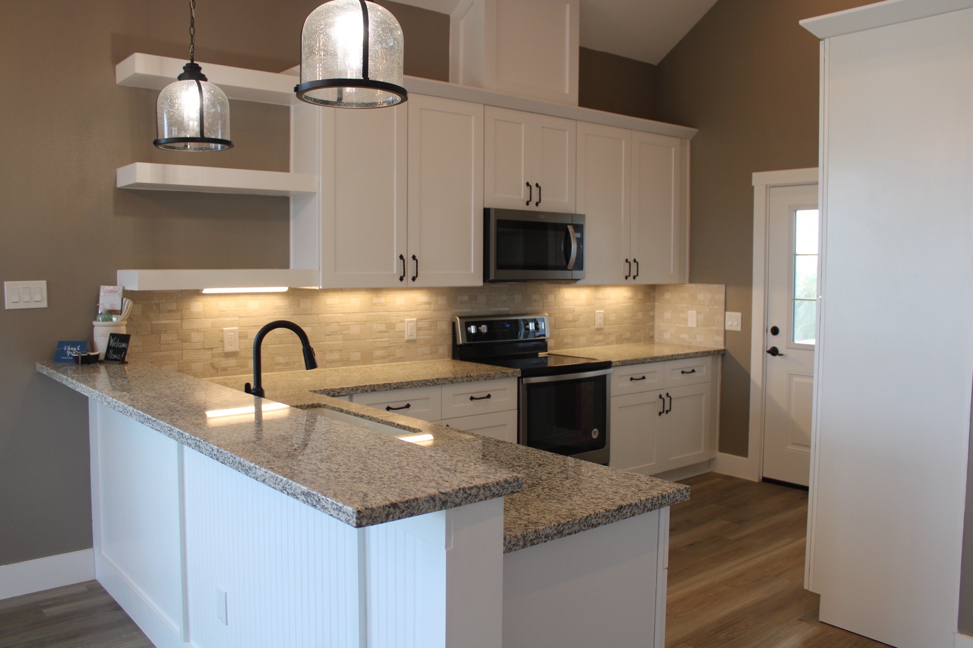 Tiled walk-in shower with black matte showerhead and handles, neutral stone-look tile, and glass enclosure in the guest bathroom