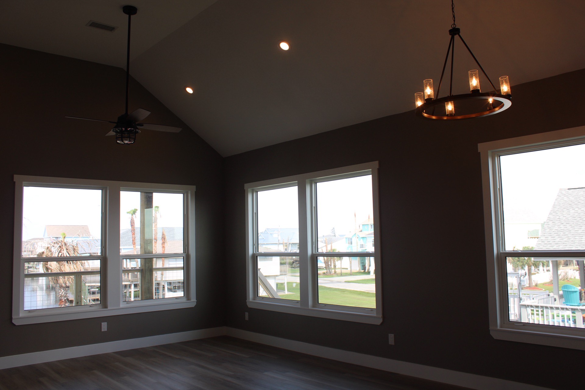 Stone tile backsplash and white shaker upper cabinets with black matte handles flanking the stainless steel range in the Tiki Island kitchen