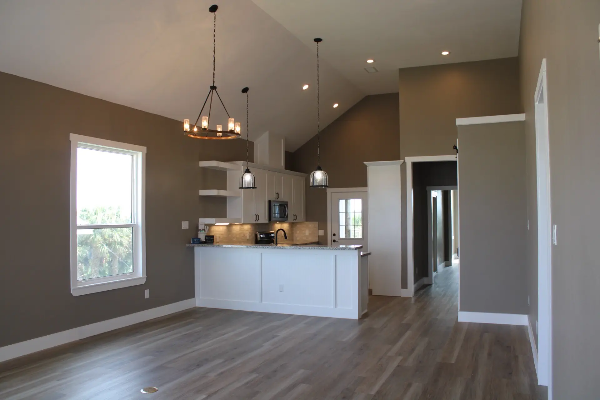 Full kitchen view showing the open layout flowing into the dining and living area with LVP wood-look flooring throughout