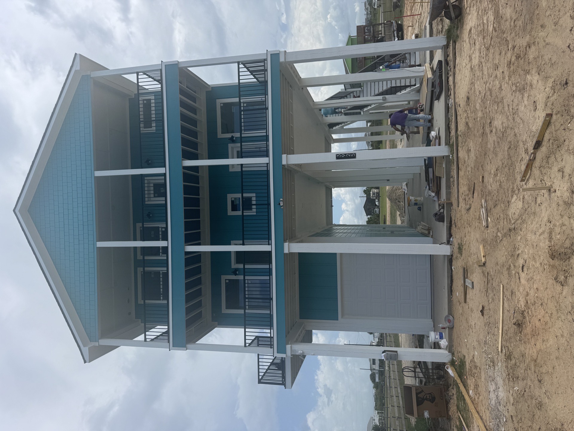 Spacious master bedroom featuring a wood-look accent wall behind the bed, high ceilings, and warm natural light in the 2nd Street coastal home