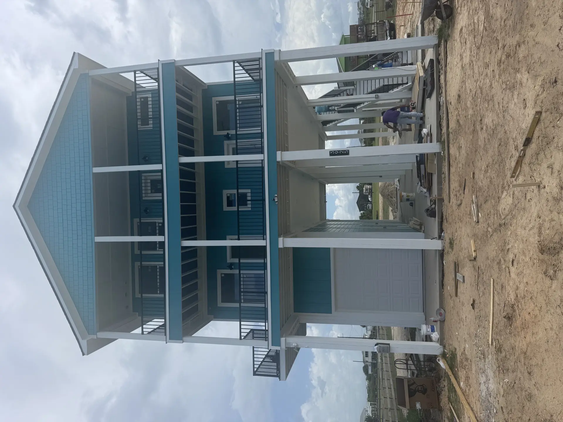 Spacious master bedroom featuring a wood-look accent wall behind the bed, high ceilings, and warm natural light in the 2nd Street coastal home