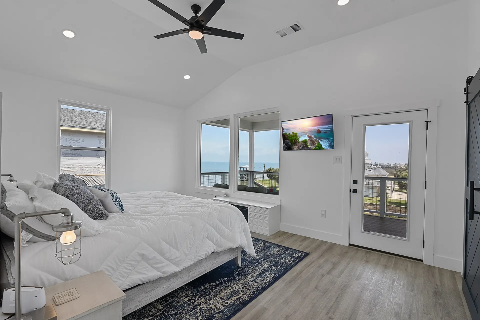 Open-concept great room with white shiplap accent wall, built-in shelving flanking the fireplace, and professionally staged coastal furnishings