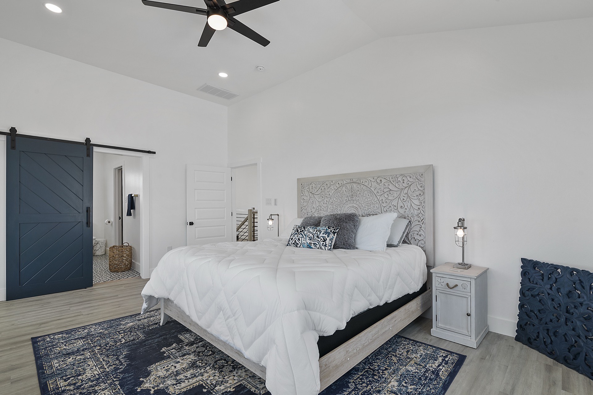 Living room seating area with neutral upholstered furniture, woven area rug, and canal views through the sliding glass doors to the covered deck