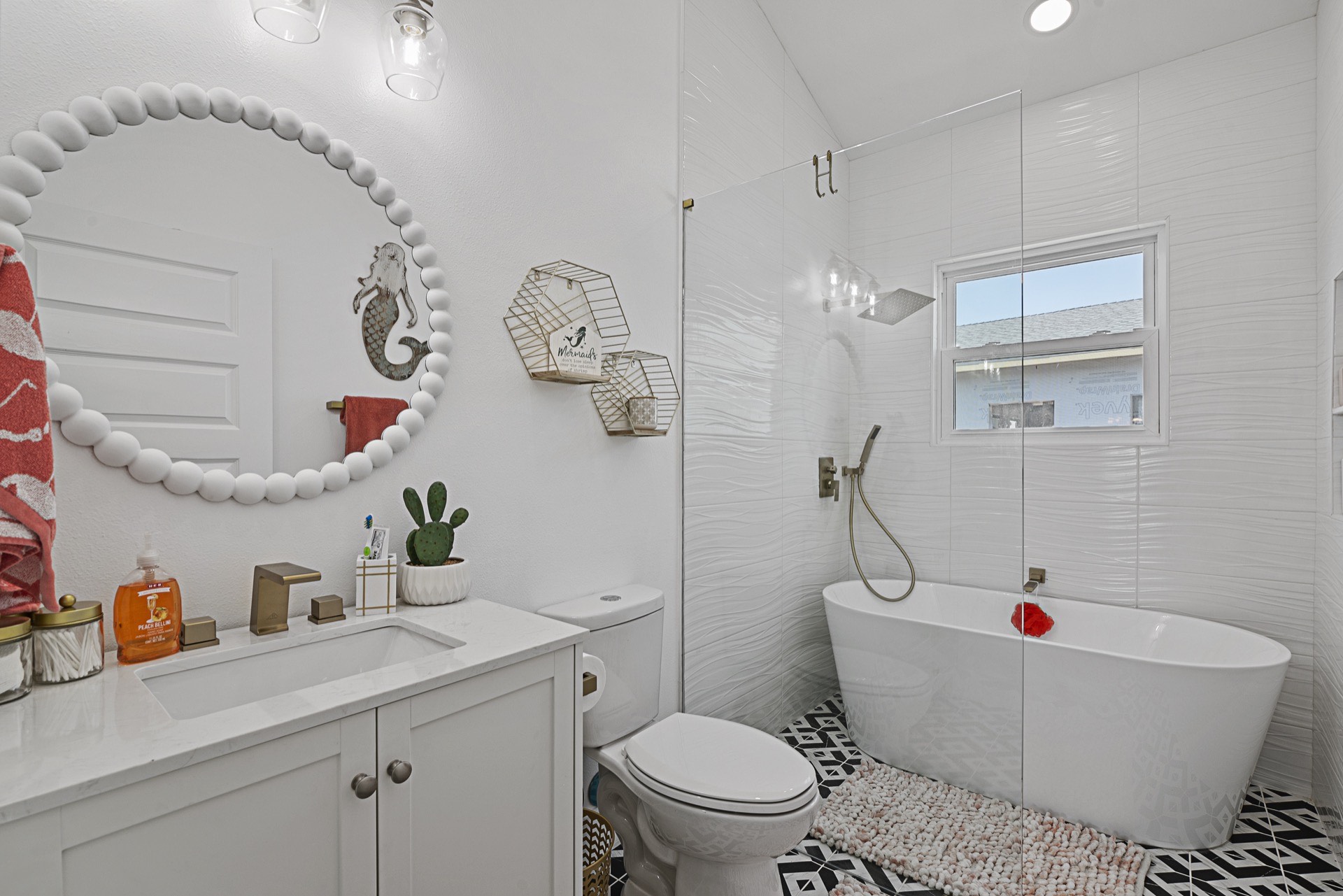 Master bathroom featuring navy blue double vanity with gold hardware, decorative black-and-white patterned floor tile, and framed mirrors