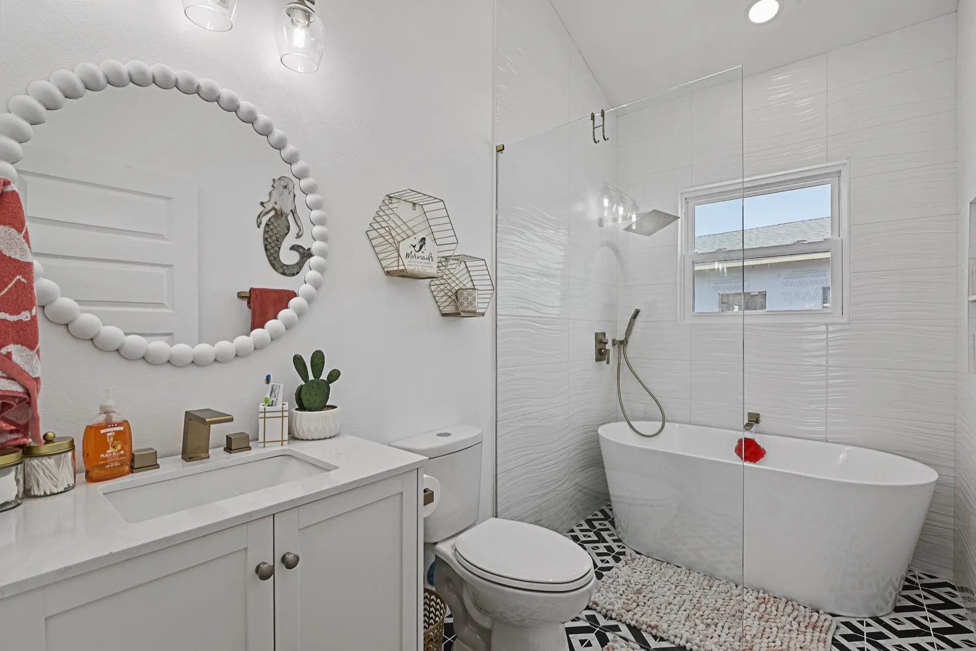 Master bathroom featuring navy blue double vanity with gold hardware, decorative black-and-white patterned floor tile, and framed mirrors