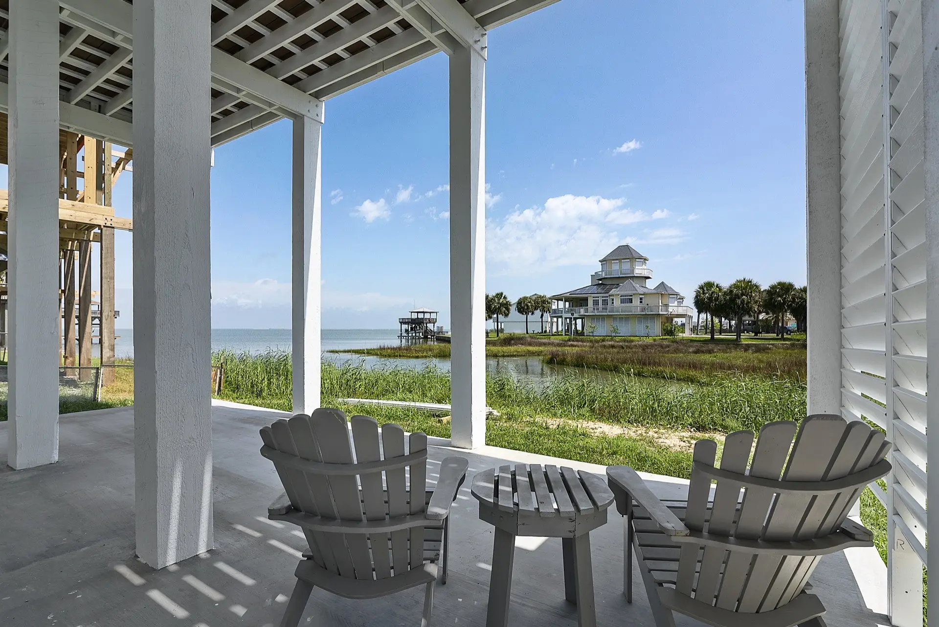 Master bedroom with neutral tones, large windows facing the canal, and professional staging with coastal-inspired linens and decor