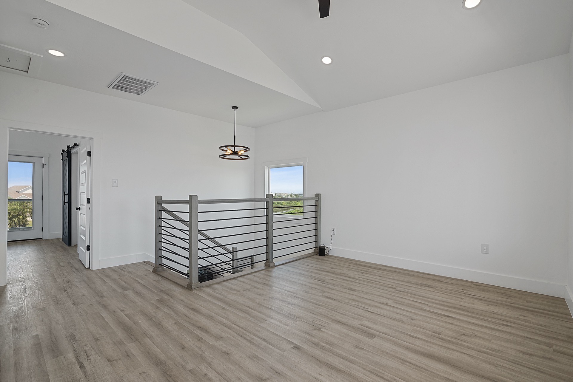 Guest bedroom with professionally staged coastal decor, light neutral walls, and wide-plank flooring in the 3742 Laguna waterfront home