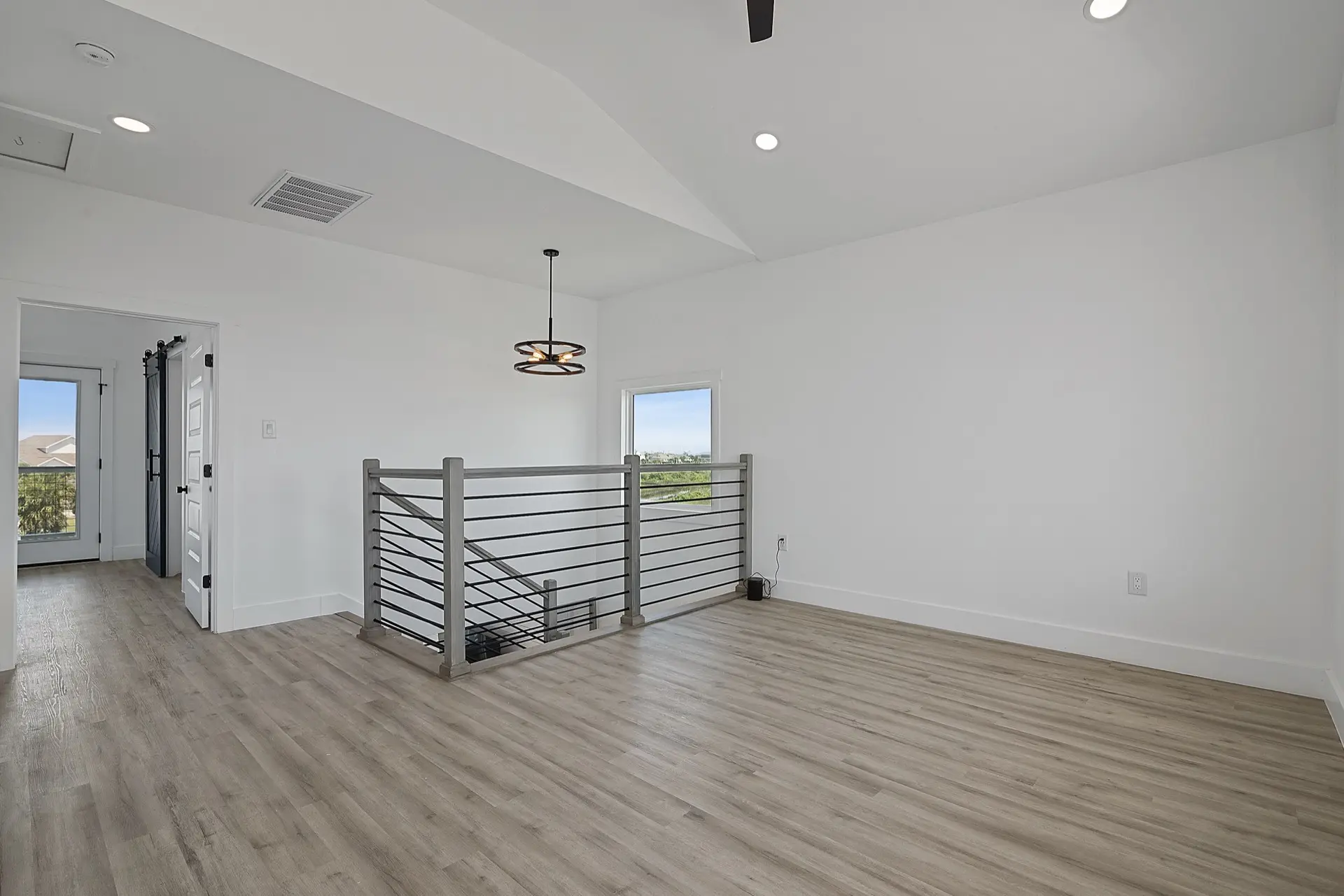 Guest bedroom with professionally staged coastal decor, light neutral walls, and wide-plank flooring in the 3742 Laguna waterfront home
