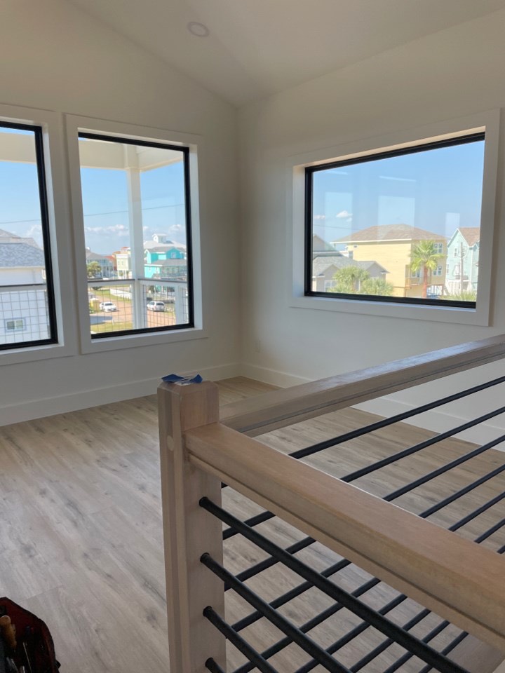 Secondary bathroom with coastal blue-green glass tile shower enclosure, brass shower fixtures and hardware, and frameless glass door