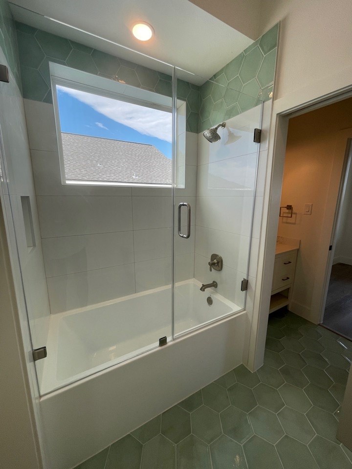 Secondary bathroom featuring handmade ceramic tile in a coastal palette, brass towel bar and fixtures, and a floating white vanity with vessel sink