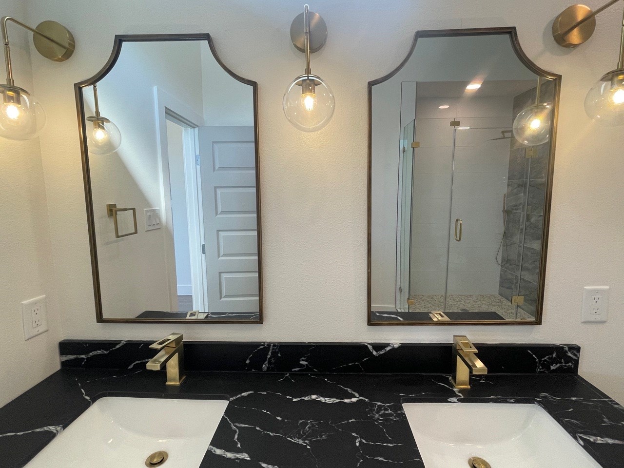 Third bathroom with patterned encaustic floor tile, white subway tile shower walls, brushed gold hardware, and a clean contemporary vanity with round mirror